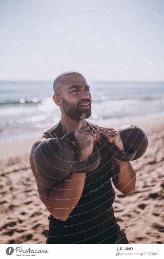 Der Sportler macht ein Wasserkochglocken-Training am Strand. Junger Mann Fitness Sport-Training hart transpirieren Muskulatur Freude Geschwindigkeit positiv