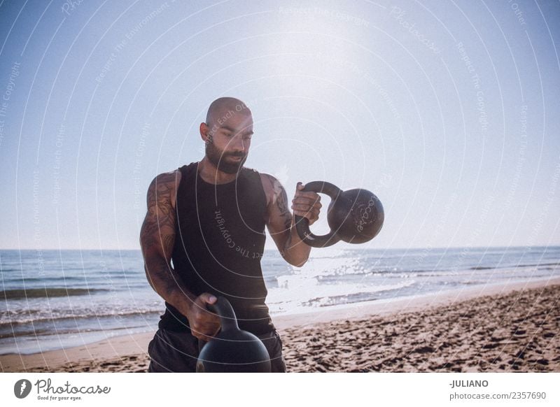 Der Sportler macht ein Wasserkochglocken-Training am Strand. Junger Mann Fitness Sport-Training Berufsausbildung hart transpirieren Muskulatur Freude