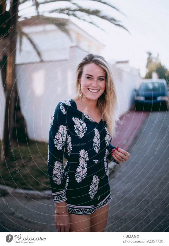 Junge stilvolle Frau, die lächelt, während sie im Sommer spazieren geht. Sonne Strand blond Coolness Abenddämmerung Freude Junge Frau gut lachen Lifestyle Meer