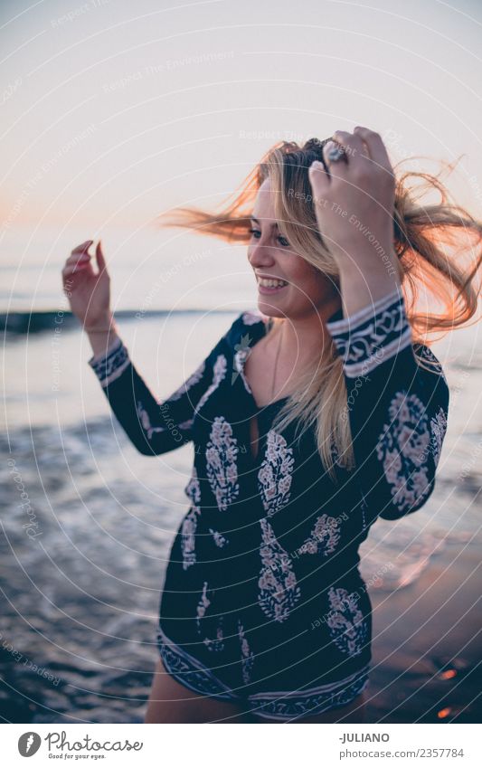 Junge Frau am Strand, während der Sonnenuntergang lächelt. blond Coolness Abenddämmerung Freude Mädchen gut Güte lachen Lifestyle Meer retro Sand Lächeln Sommer