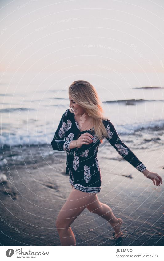 Junge Frau am Strand, die am Meer rennt und lacht. Sonne blond Coolness Abenddämmerung Freude gut Güte lachen Lifestyle retro Sand Lächeln Sommer