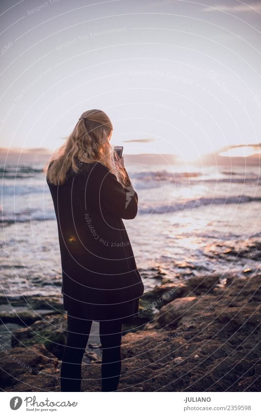 Junge Frau fotografiert den Sonnenuntergang am Strand. Abenddämmerung Gefühle Glück Leben Lifestyle Spanien Sommer Wärme Abenteuer Kommunizieren Mitteilung