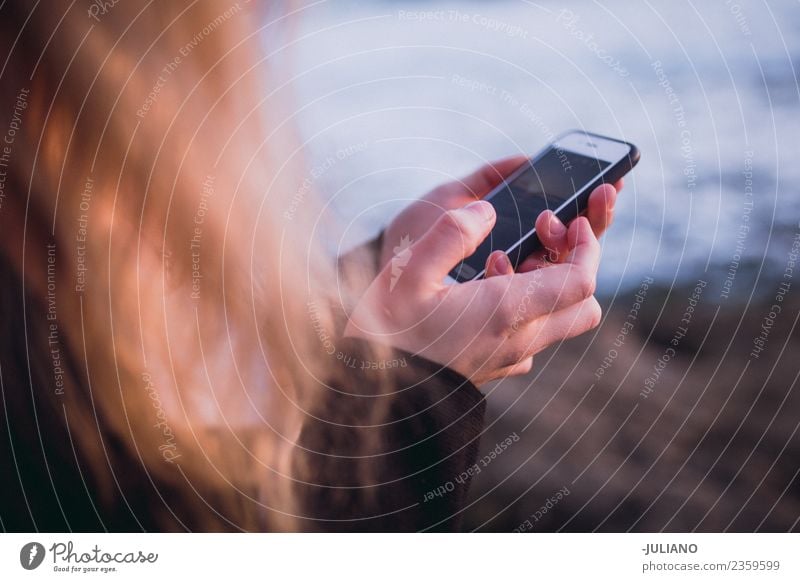 Junge Frau hält Smartphone in den Händen am Strand. Abenddämmerung Gefühle Glück Leben Lifestyle Spanien Sommer Sonne Sonnenuntergang Wärme Abenteuer Freiheit