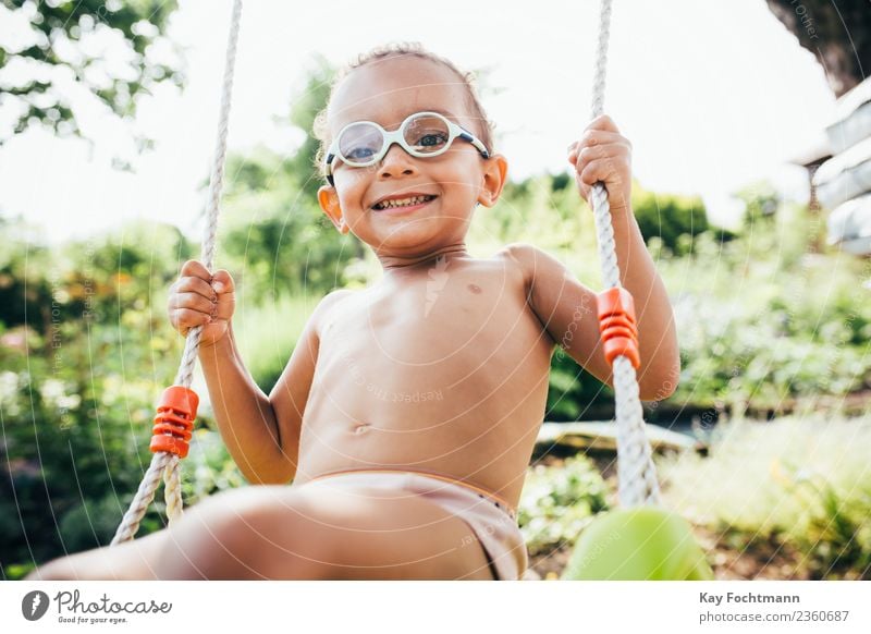 Cute black boy having fun on a swing in his parents garden Lifestyle Freude Sommer Mensch Kleinkind Junge Familie & Verwandtschaft Kindheit Leben 1 1-3 Jahre