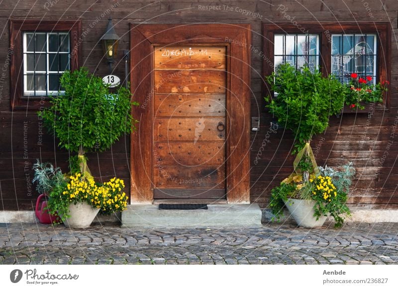 Bauernhaus Dorf Haus Hütte Mauer Wand Fassade Tür Fußmatte braun Holz Holzhaus Sträucher Eingang rustikal gepflegt Idylle Farbfoto mehrfarbig Außenaufnahme