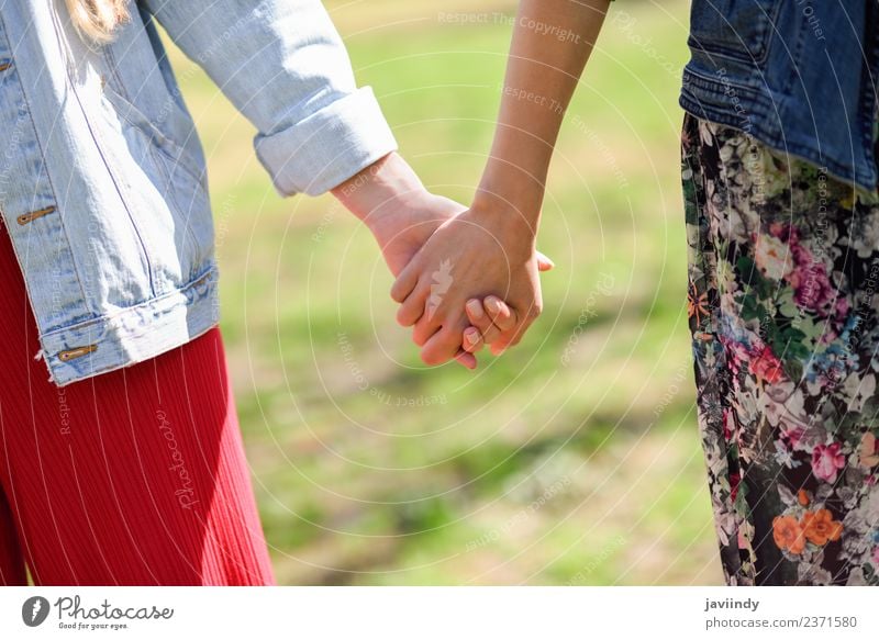 Zwei junge Frauen beim Gehen, die ihre Hände halten. Lifestyle Freude Glück schön Mensch Junge Frau Jugendliche Erwachsene Freundschaft Paar Hand 2 18-30 Jahre