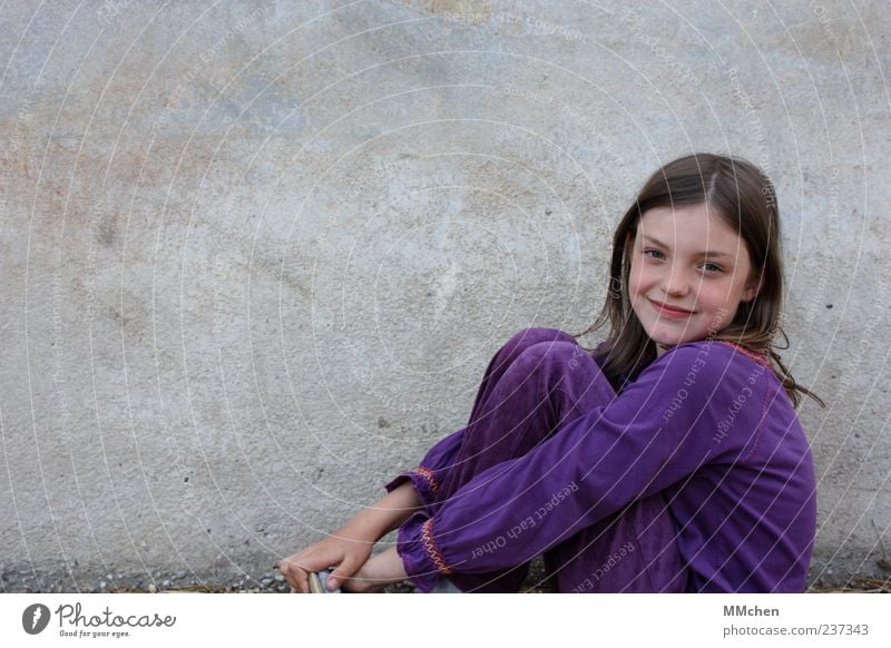 Ich kann in 3 Sekunden die Welt erobern Kind Mädchen Kindheit 1 Mensch 8-13 Jahre Mauer Wand langhaarig Scheitel Blick sitzen grau violett Glück Fröhlichkeit