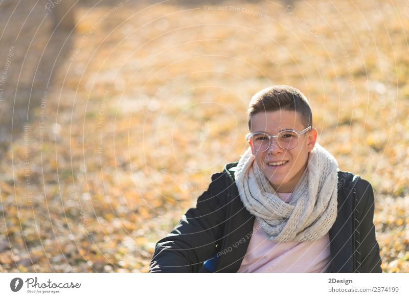 Stylisch lächelnder Teenager auf dem Boden in einem Stadtpark. Lifestyle Freude Glück Schulkind Studium PDA Mensch maskulin Junge Junger Mann Jugendliche