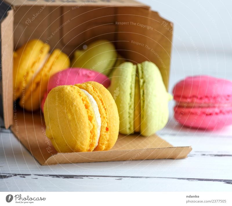 bunte Kuchen aus Mandelmehl Dessert Süßwaren Tisch Papier Holz Essen hell gelb grün rosa weiß Farbe Macaron Lebensmittel farbenfroh Vanille Französisch süß