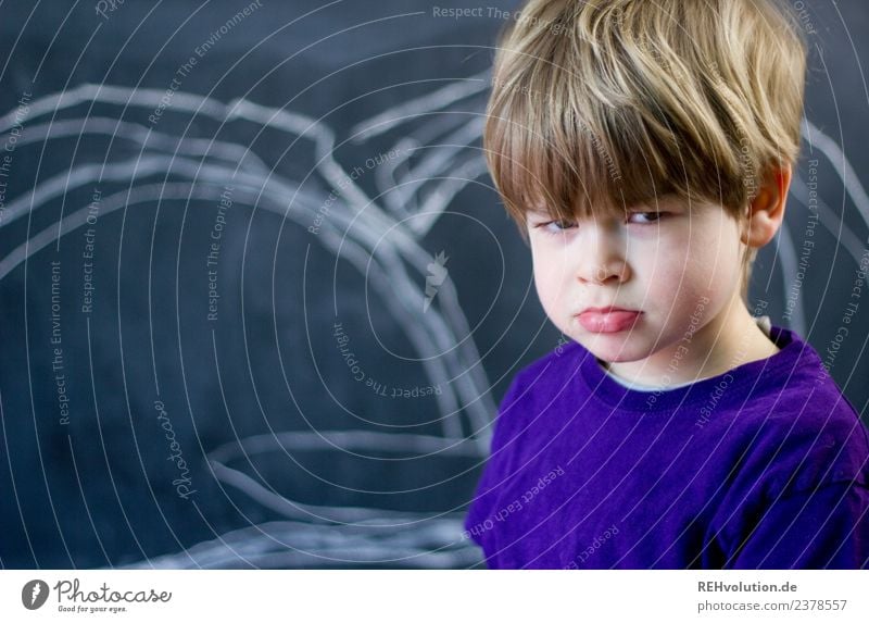 junge guckt grimmig Blick in die Kamera Vorderansicht Oberkörper Porträt Zentralperspektive Schwache Tiefenschärfe Unschärfe Tag Textfreiraum links Nahaufnahme