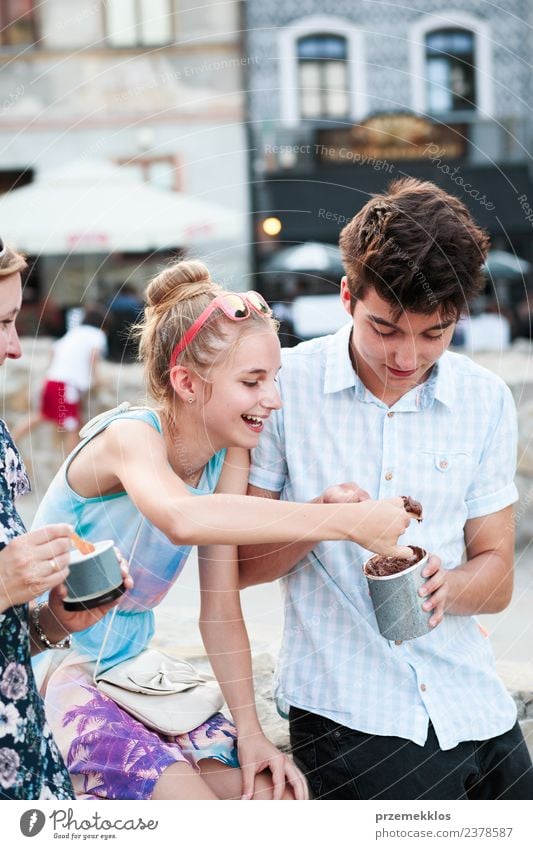 Familien, die im Stadtzentrum Zeit miteinander verbringen, genießen es, an einem Sommertag Eiscreme zu essen. Mutter, Teenager, Mädchen und Junge verbringen an sonnigen Nachmittagen viel Zeit miteinander und essen ein süßes Dessert. Stadtzentrum, Altstadt im Hintergrund