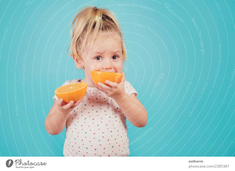 Baby isst eine Orange auf blauem Hintergrund Lebensmittel Frucht orange Ernährung Essen Mittagessen Lifestyle Freude Gesunde Ernährung Mensch feminin Mädchen