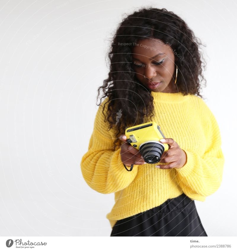 Apolline feminin Frau Erwachsene 1 Mensch Rock Pullover Ohrringe brünett langhaarig Locken Fotokamera beobachten festhalten Blick schön gelb Willensstärke