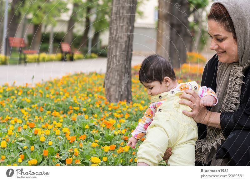 Muslimische Mutter hält kleines Baby in Frühlingsblumen im Park. Lifestyle Freude schön Leben Spielen Garten Kindererziehung Mensch Mädchen Junge Frau