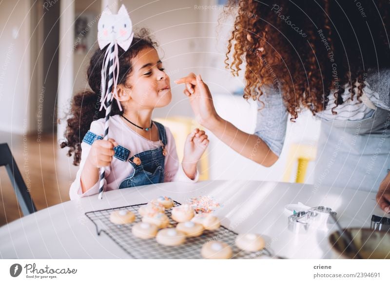 Afrikanische Mutter und Tochter genießen ihre selbstgemachten Kekse. Dessert Freude Glück schön Küche Kind Mensch Frau Erwachsene Kindheit Finger Fröhlichkeit