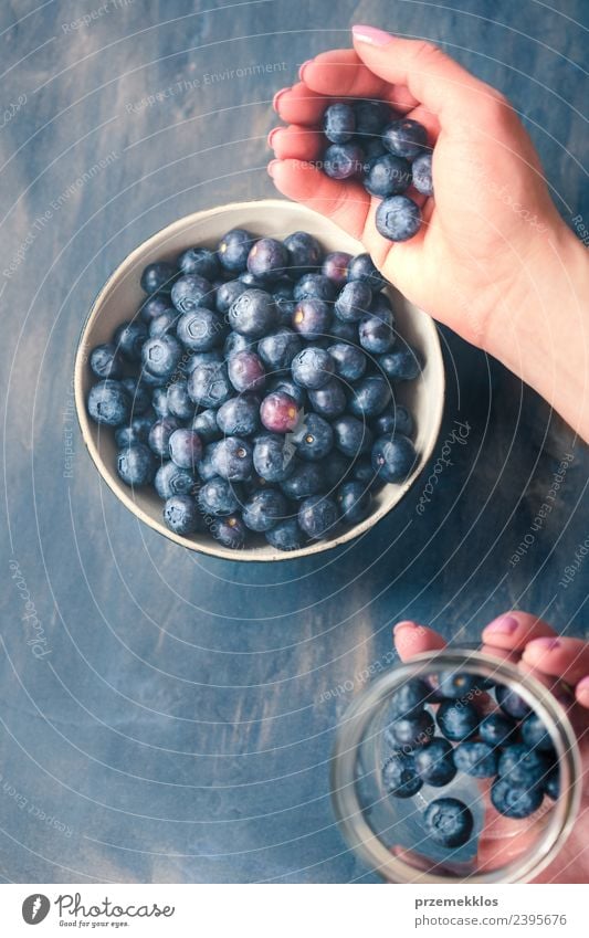 Frau, die frische Heidelbeeren aus einem Glas in eine kleine Schüssel legt. Lebensmittel Frucht Ernährung Bioprodukte Vegetarische Ernährung Diät