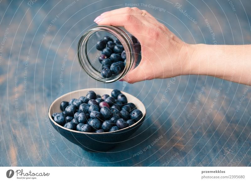 Frau, die frische Heidelbeeren aus einem Glas in eine kleine Schüssel legt. Lebensmittel Frucht Ernährung Bioprodukte Vegetarische Ernährung Diät