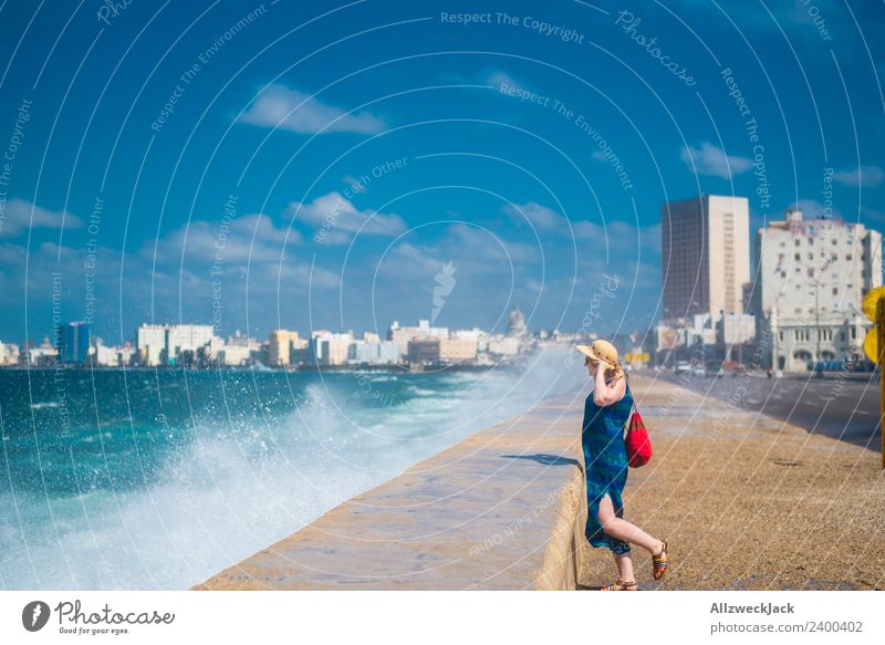 Frau mit blauem Kleid und Hut am Malecon in Havanna Tag Sommer Blauer Himmel Kuba El Malecón Meer Wasser Wellen Gischt Promenade Küste Skyline Wolken