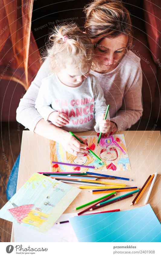 Mama mit kleiner Tochter, die die bunten Bilder zeichnet. Lifestyle Freude Glück Handarbeit Tisch Kindergarten Schule Mensch Mädchen Frau Erwachsene Eltern