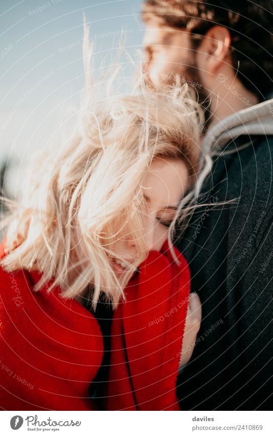 Blonde Frau umarmt ihren Freund mit geschlossenen Augen. Lifestyle Sonne Winter Erwachsene Mann Paar Mode blond Vollbart Liebe Umarmen Coolness Zusammensein