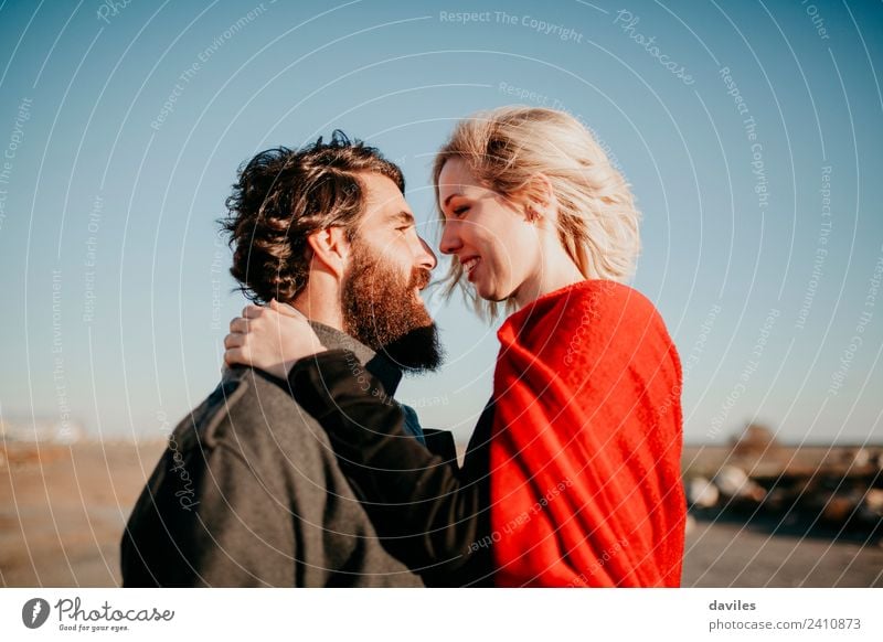 Bartiger Mann und blonde Frau schauen auf jeden. Lifestyle Freude Glück schön Sonne Winter Erwachsene Paar Mode Vollbart Küssen Lächeln Liebe Umarmen Coolness