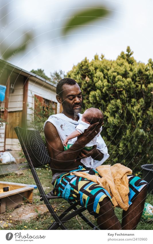 Vater sitzt im Garten und hält seinen Sohn liebevoll im Arm Glück Wohlgefühl Zufriedenheit Erholung Freiheit Sommer Sommerurlaub Häusliches Leben Baby Mann