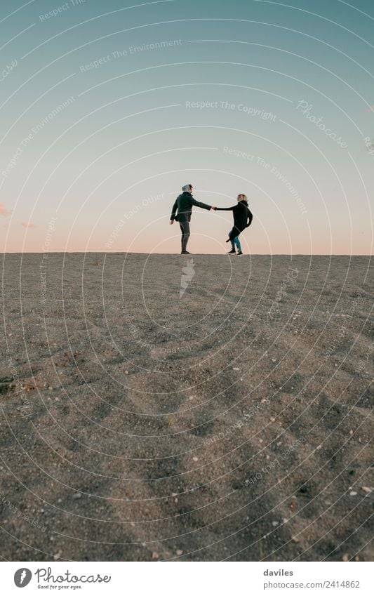 Liebliches Paar beim Spaziergang durch den Sand am Strandhorizont. Lifestyle Freude schön Winter Mensch Junge Frau Jugendliche Junger Mann Erwachsene Partner 2