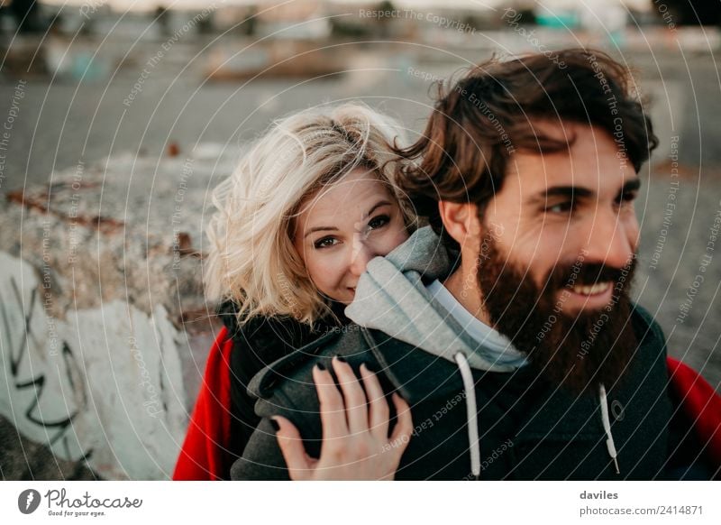 Blondes Mädchen schaut in die Kamera, während sie ihren bärtigen Freund umarmt. Lifestyle Freizeit & Hobby Mensch Junge Frau Jugendliche Junger Mann Erwachsene