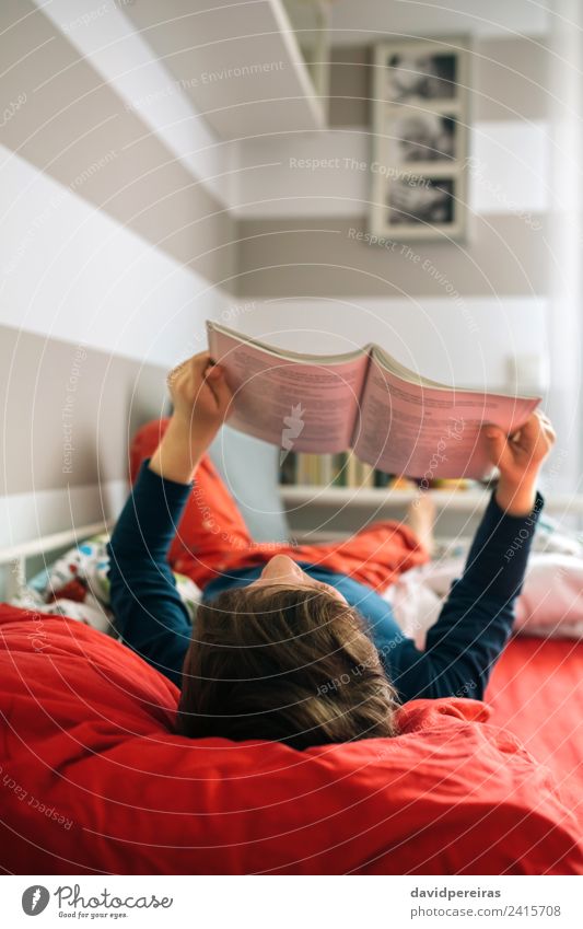 Junge liest auf seinem Bett. Lifestyle Freude schön ruhig Freizeit & Hobby lesen Schlafzimmer Kind Mensch Mann Erwachsene Kultur Buch Spielzeug authentisch