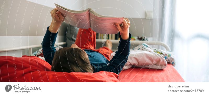 Junge liest auf seinem Bett. Lifestyle Freude ruhig Freizeit & Hobby lesen Schlafzimmer Kind Mensch Mann Erwachsene Kultur Buch Spielzeug authentisch niedlich