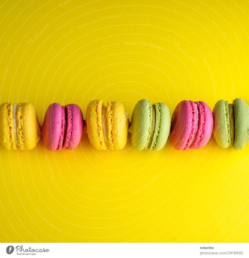 macarons liegt in einer Reihe in der Mitte. Dessert Süßwaren Essen hell gelb grün rosa Farbe Idee Macaron Hintergrund Lebensmittel farbenfroh Vanille