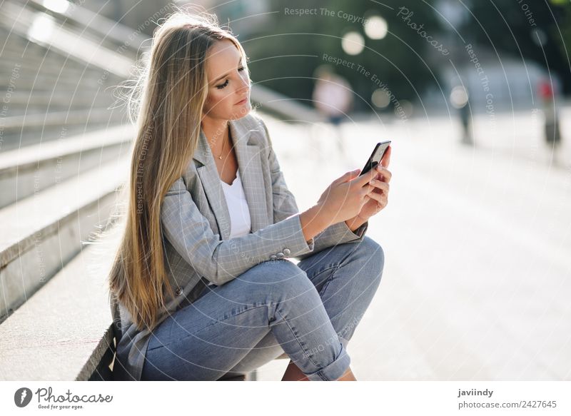 Blonde Frau, die ihr Smartphone im Freien ansieht. Lifestyle Stil schön Haare & Frisuren Telefon PDA Mensch Junge Frau Jugendliche Erwachsene 1 18-30 Jahre