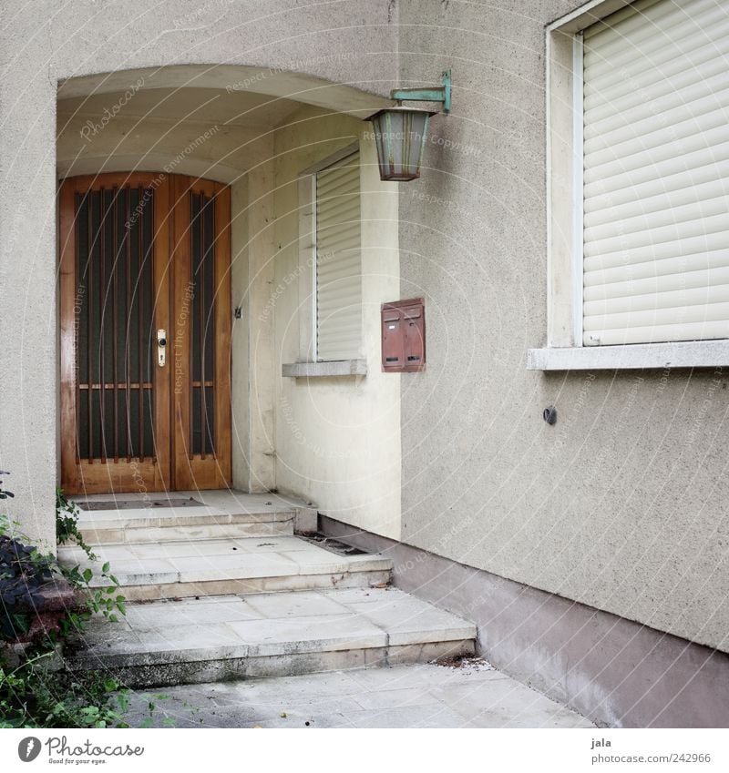 verreist Pflanze Sträucher Grünpflanze Haus Einfamilienhaus Bauwerk Gebäude Architektur Mauer Wand Treppe Fassade Fenster Tür Briefkasten Laterne alt trist