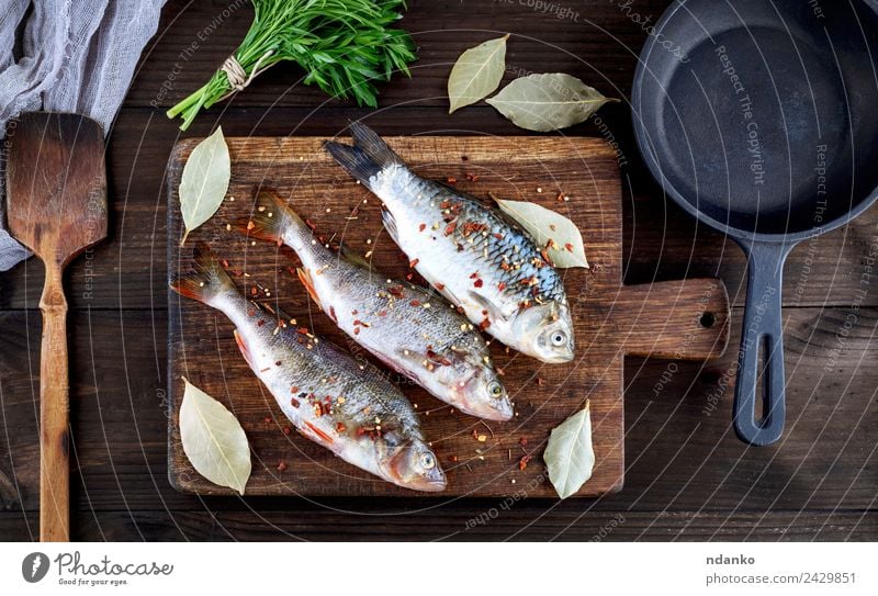 Fisch auf einem braunen Holzbrett Meeresfrüchte Kräuter & Gewürze Ernährung Abendessen Diät Pfanne Tisch Tier Fluss dunkel frisch oben retro schwarz Barsch