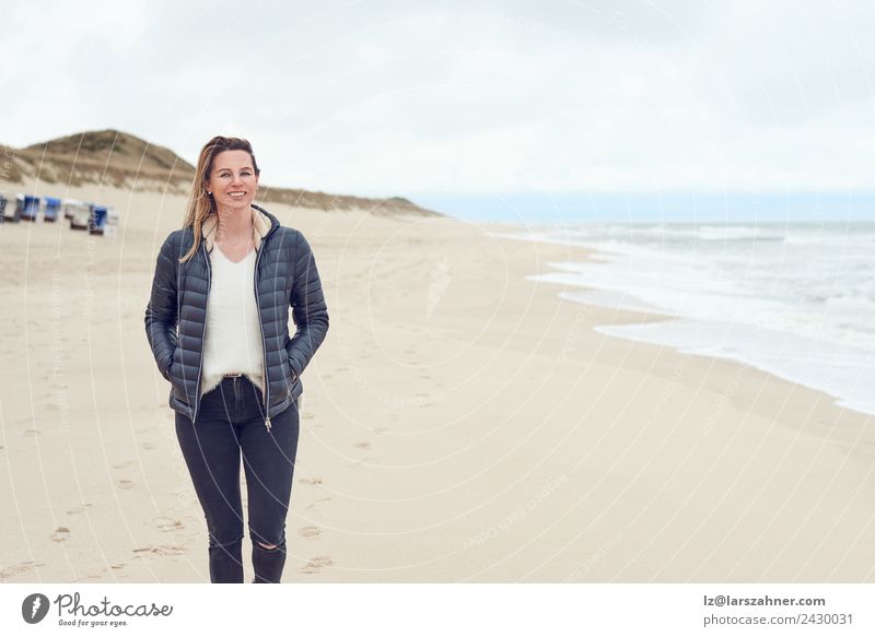 Frau, die an einem bewölkten Tag am Strand spazieren geht. Freizeit & Hobby Freiheit Meer Erwachsene 1 Mensch 45-60 Jahre Sand Wolken Herbst Küste Nordsee