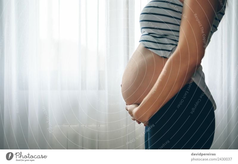 Schwangere Frau hält ihren Bauch. Lifestyle schön Leben Schlafzimmer Kindererziehung Mensch Baby Erwachsene Eltern Mutter Liebe warten authentisch Fröhlichkeit