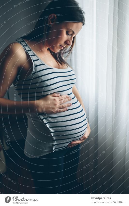 Schwangere Frau, die ihren Bauch ansieht. Lifestyle schön Leben Kindererziehung Mensch Baby Erwachsene Eltern Mutter Hand Denken Liebe Wachstum warten