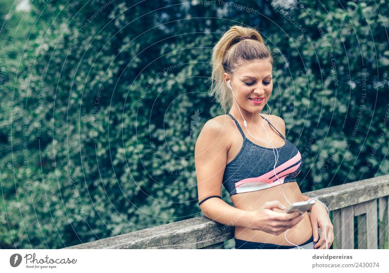 Frau in Sportbekleidung mit Kopfhörern, die wie ein Smartphone aussehen. Lifestyle Freude Glück Musik Telefon PDA Technik & Technologie Mensch Erwachsene Hand