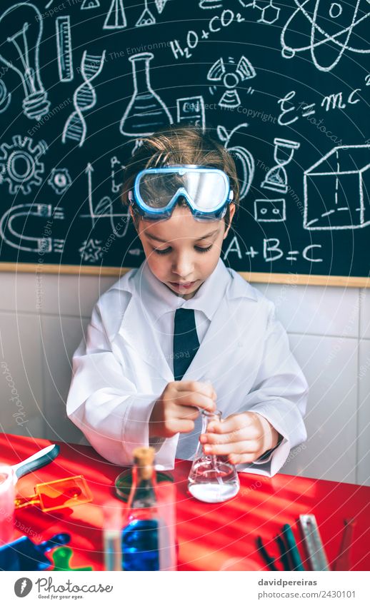 Ernsthaftes Kind beim Spielen mit chemischen Flüssigkeiten Flasche Glück Wohnung Tisch Wissenschaften Klassenraum Tafel Labor Mensch Junge Kindheit Hand