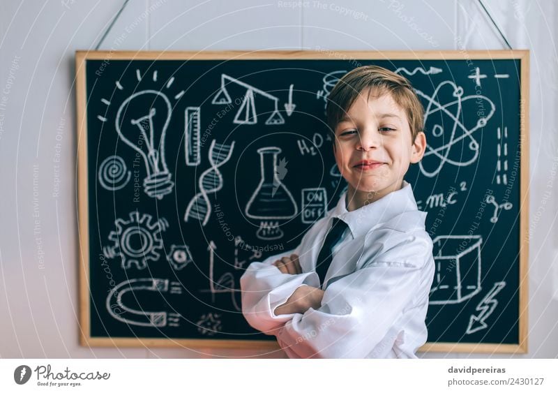 Lächelndes Kind, das vor der Tafel auf die Kamera schaut. Glück Spielen Wohnung Wissenschaften Klassenraum Labor Mensch Junge Kindheit lachen authentisch klein