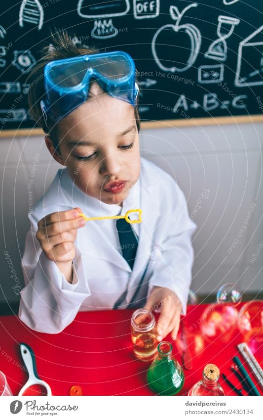 Kind, das Seifenblasen gegen eine gemalte Tafel macht. Flasche Freude Glück Spielen Wohnung Tisch Wissenschaften Schule Klassenraum Labor Mensch Junge Kindheit