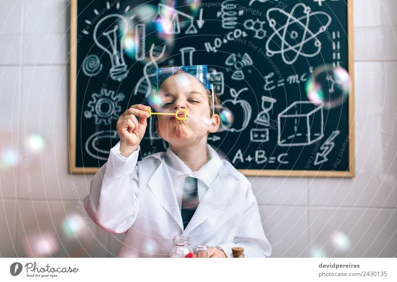 Kind, das Seifenblasen gegen eine gemalte Tafel macht. Freude Glück Spielen Wohnung Wissenschaften Schule Klassenraum Labor Mensch Junge Kindheit authentisch