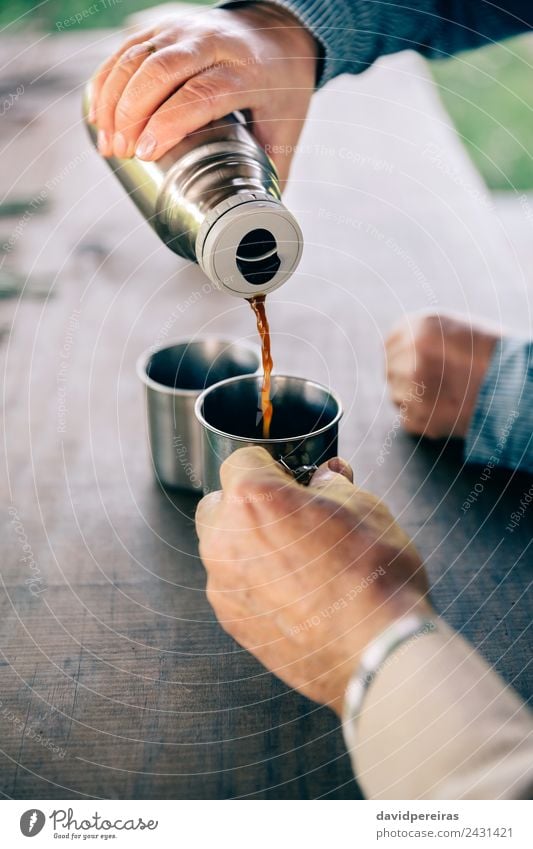 Senior Paar Hände gießen Kaffee aus der Thermoskanne. trinken Tee Lifestyle Erholung Freizeit & Hobby Tisch Mensch Frau Erwachsene Mann Hand Holz Metall alt