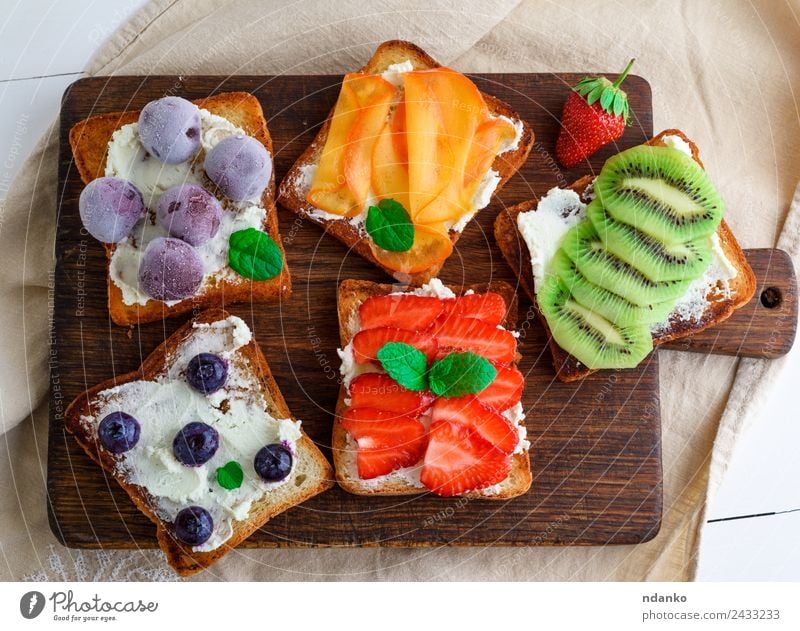 Französische Toasts mit Weichkäse Käse Frucht Brot Dessert Frühstück Holz Essen oben weich grün weiß Erdbeeren Zuprosten Kiwi Blaubeeren Molkerei Walnussholz