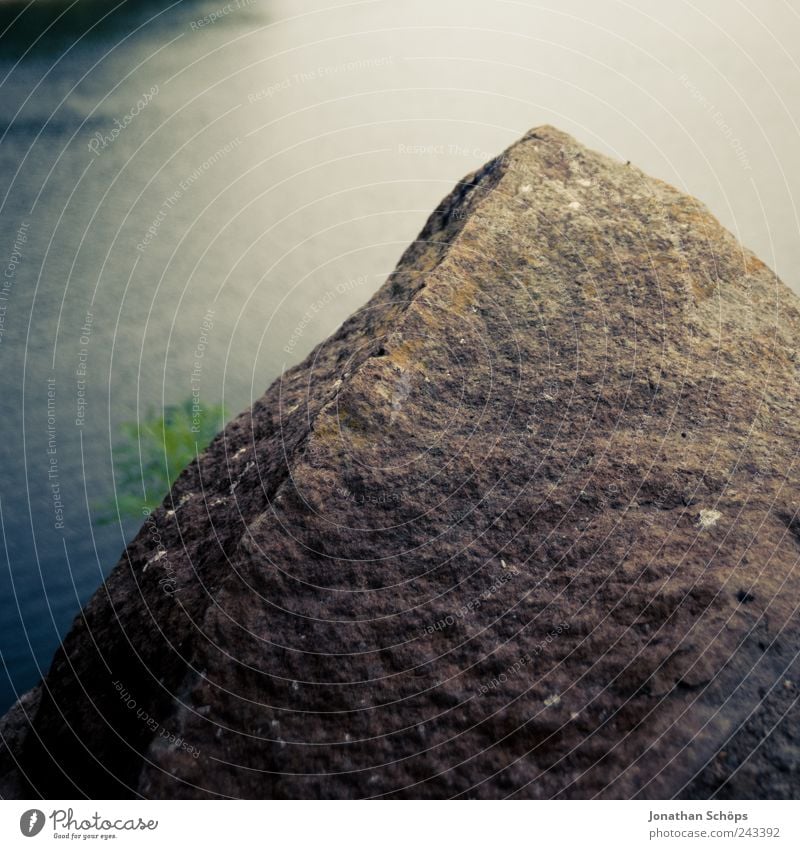 Der Felsen vor dem Wasser Umwelt Natur Urelemente Küste Seeufer Flussufer blau braun grün Stein steinig Stausee Quadrat Blick Strukturen & Formen Oberfläche