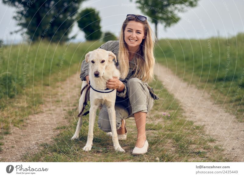 Fröhliche junge blonde Frau mit ihrem Hund Lifestyle Glück schön Gesicht Sommer Erwachsene Freundschaft 1 Mensch 18-30 Jahre Jugendliche Natur Tier Straße