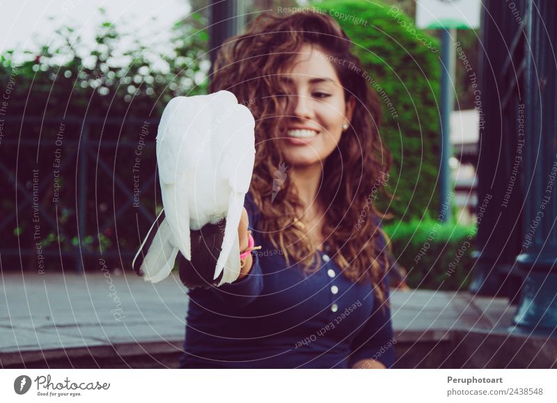 Eine lächelnde Frau, die eine Taube aus ihrer Hand füttert. Freude Glück schön Leben Freiheit Sommer Küche Mensch Erwachsene Arme Natur Tier Wärme Park Vogel