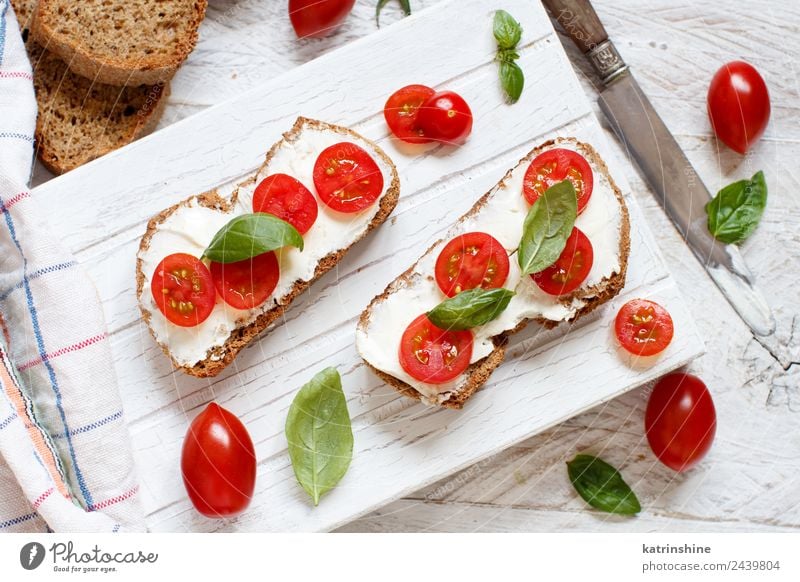 Bruschetta mit Frischkäse, Kirschtomaten und Basilikum Käse Brot Essen Frühstück Mittagessen frisch grün Amuse-Gueule Baguette Holzplatte Essen zubereiten Sahne