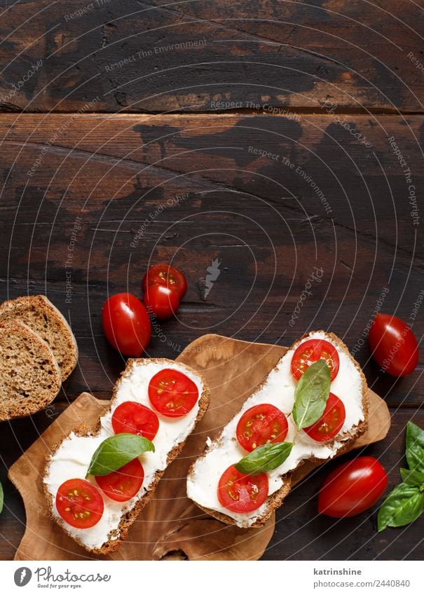 Bruschetta mit Frischkäse, Kirschtomaten und Basilikum Käse Brot Essen Frühstück Mittagessen frisch grün Amuse-Gueule Baguette Holzplatte Essen zubereiten Sahne