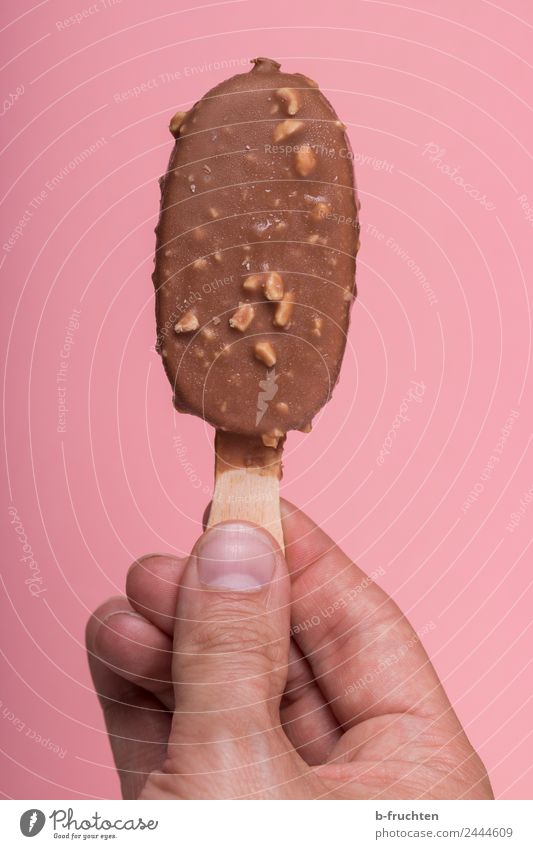 Eis am Stiel Speiseeis Mann Erwachsene Hand Finger Essen festhalten frisch braun rosa genießen stieleis Besenstiel Sommer kalt Mandel Schokolade Zuckerguß